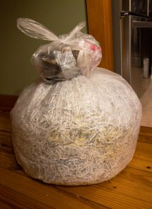 Stacked bags of trash, the lower one containing shredded documents.