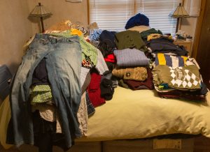 Piles of clothing covering a bed.